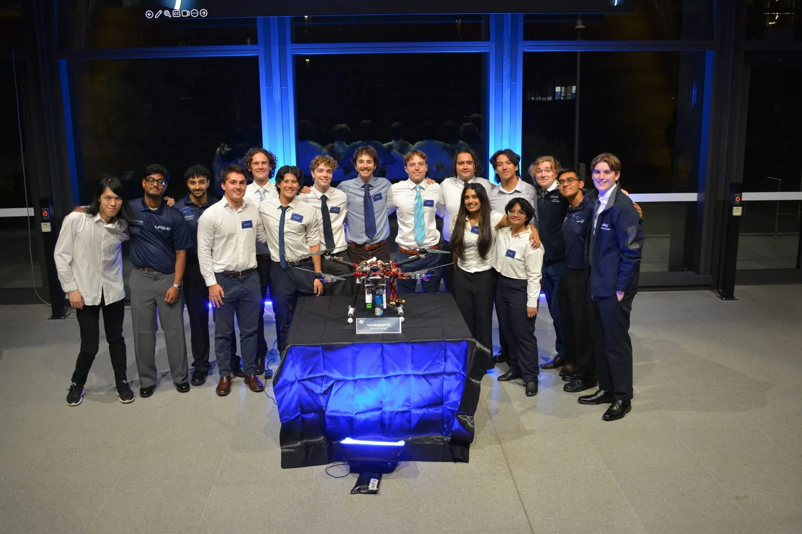Monash UAS members gathered around an aircraft display
